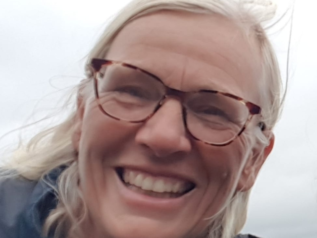 An image of a smiling, white woman with white hair and glasses