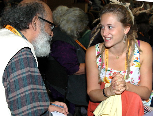 At a conference a young blonde woman talks to older man with smiles