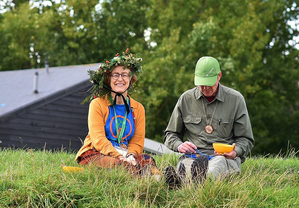 Helen wearing a hat in a field alongside a man eating lunch