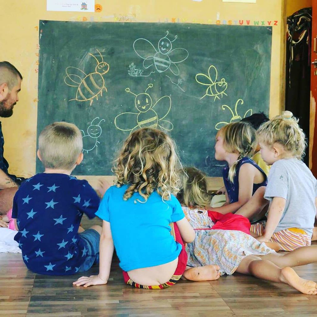 Children around a blackboard with bees on it in chalk