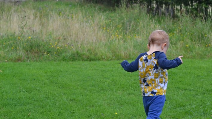Young child playing at the edge of a meadow
